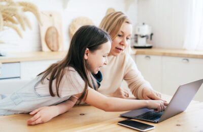 Mom and daughter surf in a laptop. Business woman with her daughter. Remote work. Freelance home life. Working mom.